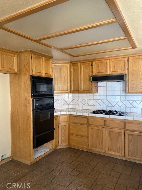 kitchen featuring black appliances, tasteful backsplash, and tile countertops