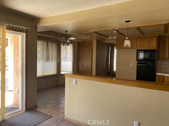 kitchen featuring ceiling fan, pendant lighting, kitchen peninsula, tasteful backsplash, and black appliances