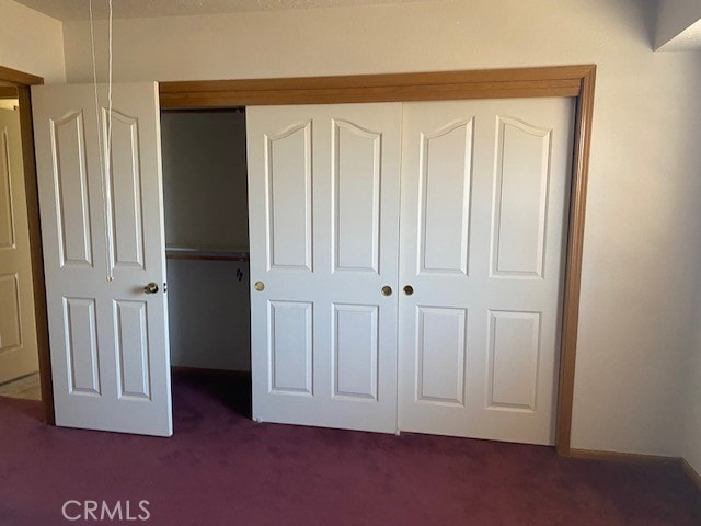 unfurnished bedroom featuring dark colored carpet and a closet