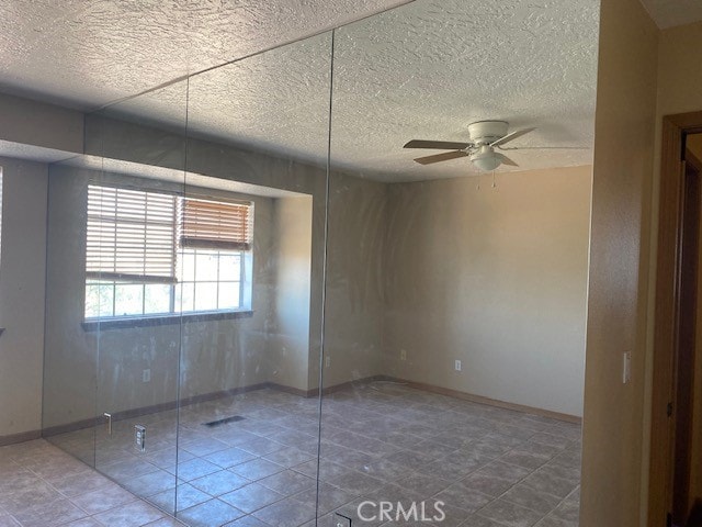 empty room featuring a textured ceiling and ceiling fan