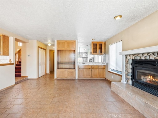 8187 Anaconda Ave, Oak Hills, CA 92344 - kitchen featuring baseboards, a fireplace, light countertops, and glass insert cabinets