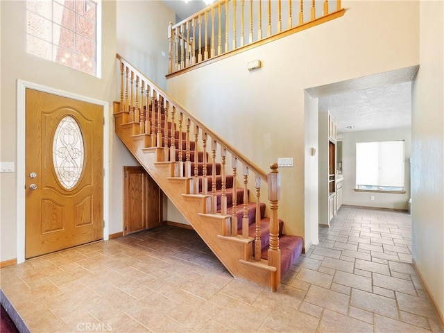 8187 Anaconda Ave, Oak Hills, CA 92344 - foyer featuring baseboards, stairway, a towering ceiling, and stone tile flooring