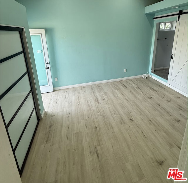 spare room with a barn door and light hardwood / wood-style flooring