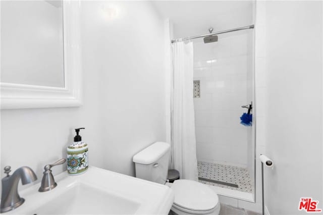 bathroom featuring toilet, curtained shower, and sink