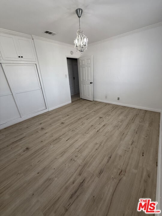 interior space with ornamental molding, a chandelier, and light wood-type flooring