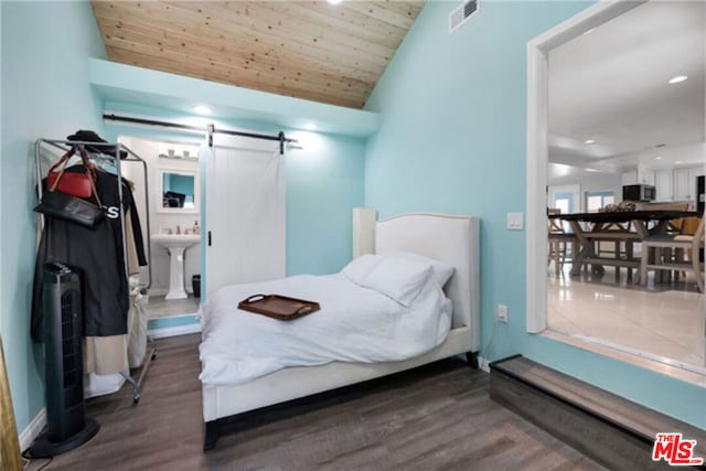 bedroom with lofted ceiling, wood ceiling, dark hardwood / wood-style floors, ensuite bathroom, and a barn door