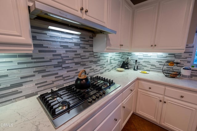 kitchen with stainless steel gas stovetop, decorative backsplash, and white cabinets