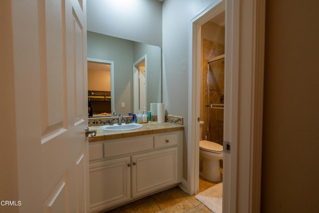 bathroom featuring tile patterned flooring, vanity, toilet, and a shower with shower door