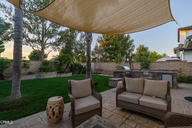 patio terrace at dusk featuring area for grilling and a lawn