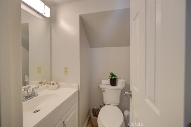 bathroom with vanity, lofted ceiling, and toilet