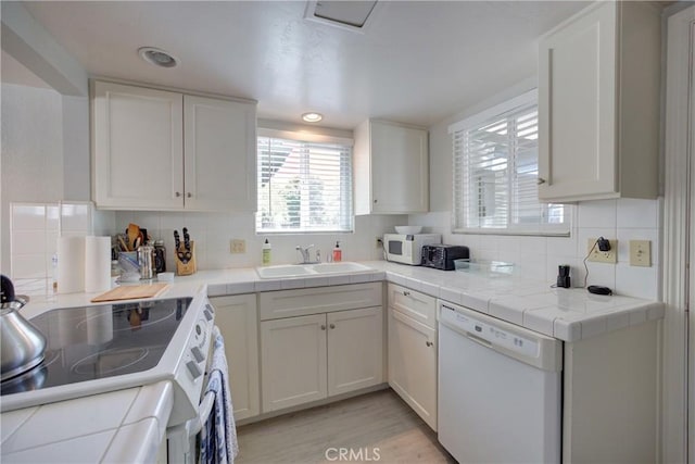 kitchen with sink, white appliances, tile countertops, and white cabinets