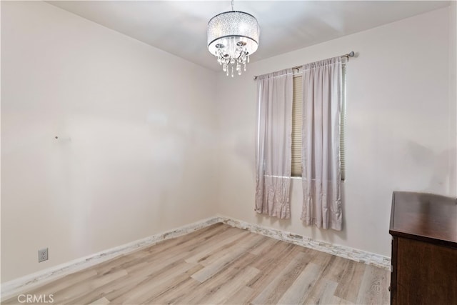 unfurnished room featuring a chandelier and light hardwood / wood-style floors