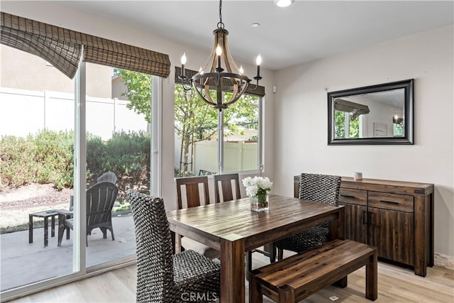 dining area with a wealth of natural light, light wood-type flooring, and an inviting chandelier