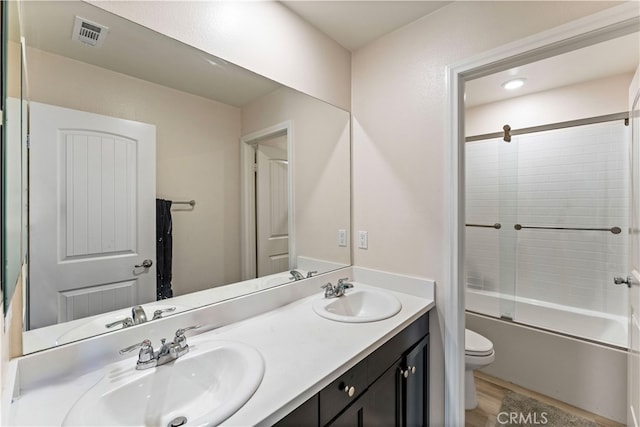 full bathroom featuring vanity, toilet, enclosed tub / shower combo, and hardwood / wood-style floors