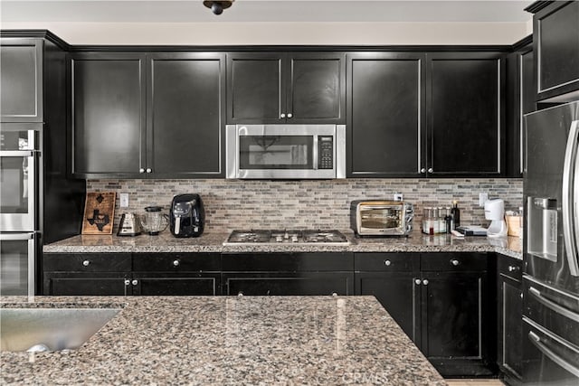 kitchen with light stone countertops, tasteful backsplash, and appliances with stainless steel finishes