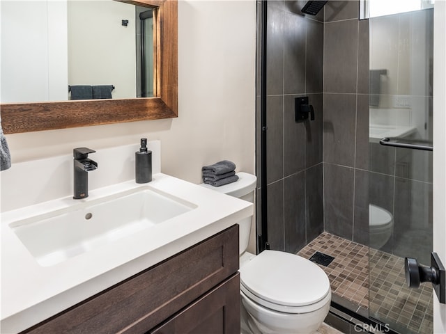 bathroom with a shower with door, vanity, and toilet