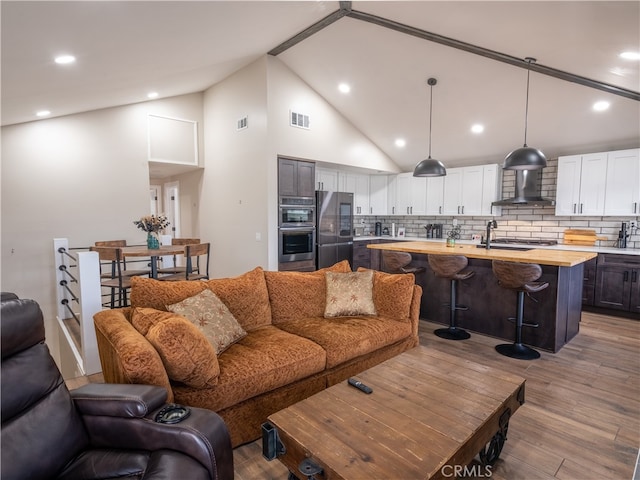 living room with light hardwood / wood-style floors and high vaulted ceiling