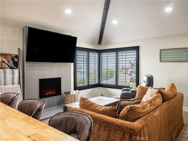 living room with lofted ceiling with beams, a tile fireplace, and hardwood / wood-style floors