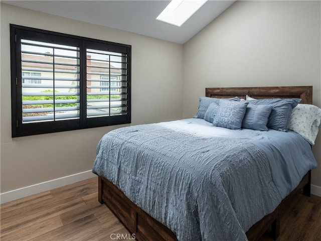 bedroom with vaulted ceiling with skylight and dark hardwood / wood-style flooring