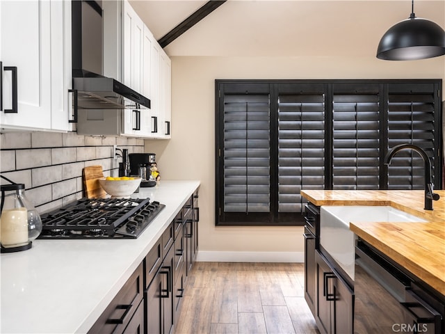 kitchen with wall chimney exhaust hood, light hardwood / wood-style flooring, black gas cooktop, decorative light fixtures, and white cabinets