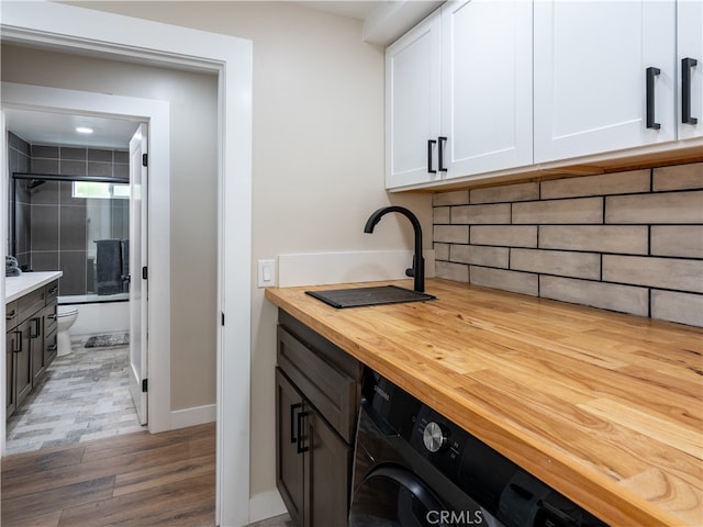 clothes washing area with cabinets, washer / clothes dryer, hardwood / wood-style flooring, and sink