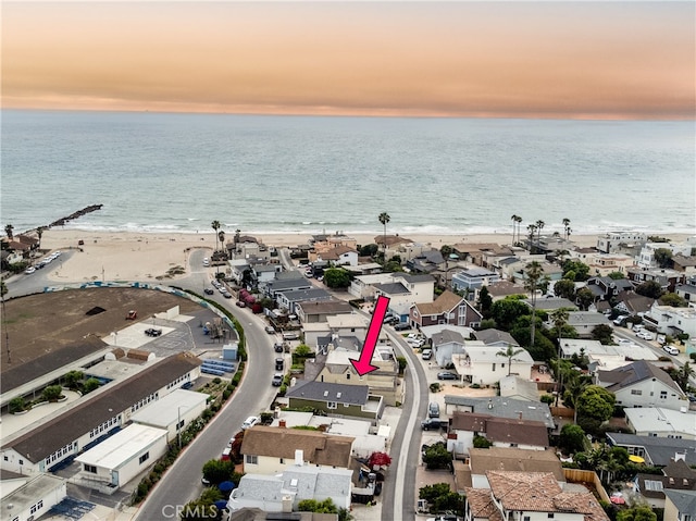 aerial view at dusk with a water view and a beach view