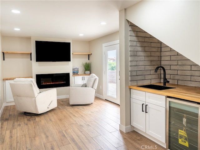 interior space with wine cooler, light wood-type flooring, and indoor wet bar