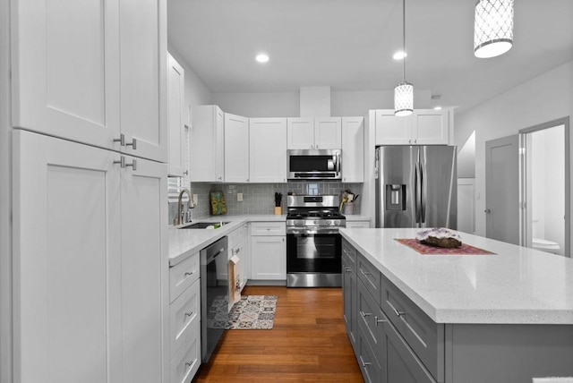 kitchen with appliances with stainless steel finishes, gray cabinetry, white cabinets, dark hardwood / wood-style flooring, and sink