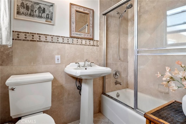 bathroom featuring tile walls, tile patterned flooring, shower / bath combination with glass door, and toilet