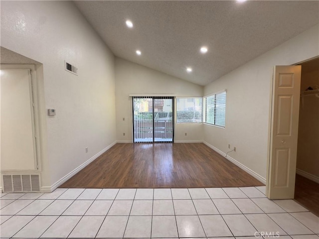 empty room featuring light tile patterned flooring and high vaulted ceiling