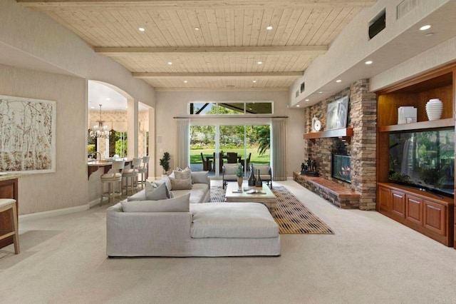 carpeted living room featuring an inviting chandelier, a fireplace, beam ceiling, and wooden ceiling