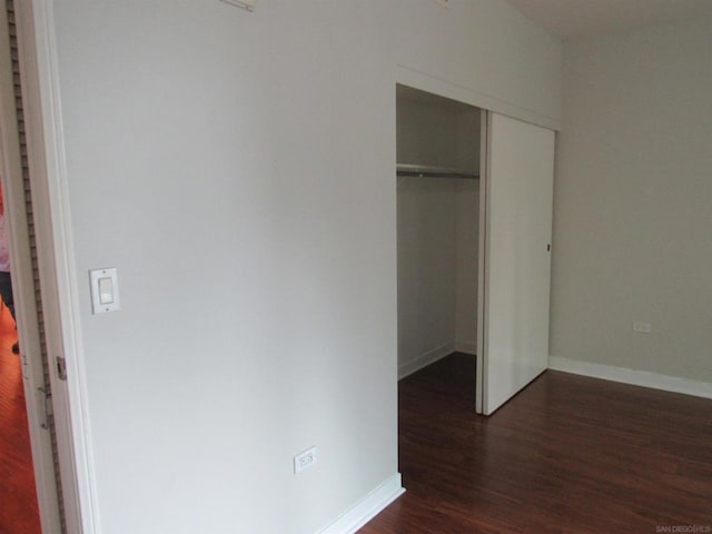 unfurnished bedroom with a closet and dark hardwood / wood-style flooring