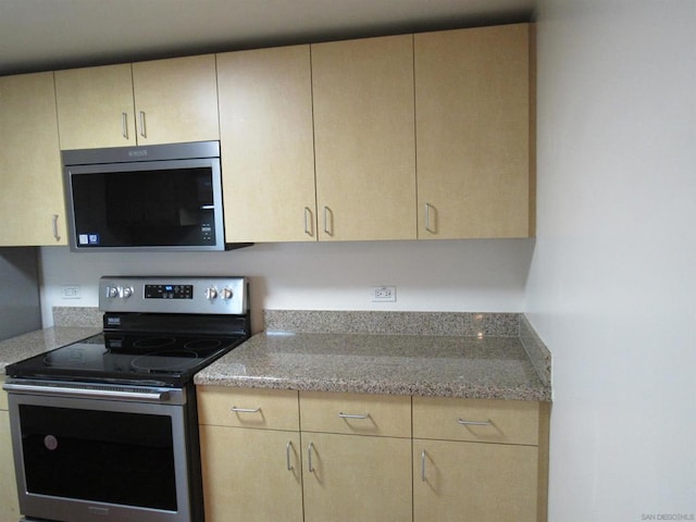 kitchen with stainless steel appliances, light stone counters, and light brown cabinetry