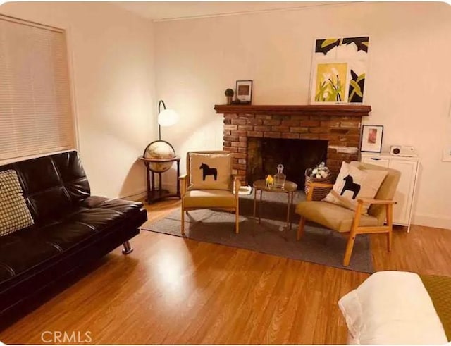 living room with a fireplace, baseboards, and wood finished floors