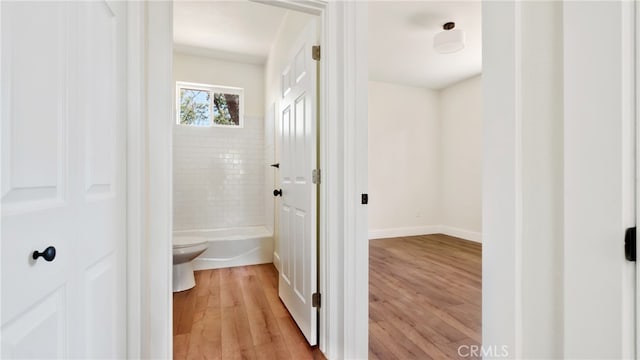 bathroom featuring hardwood / wood-style flooring, tiled shower / bath combo, and toilet