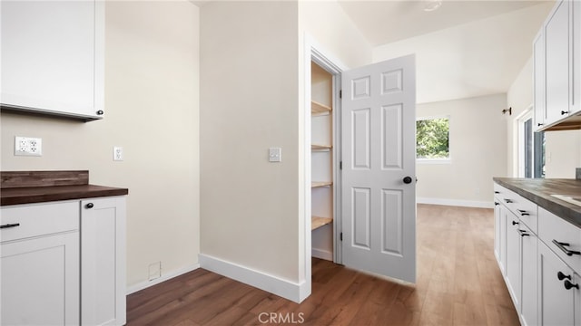 kitchen featuring white cabinets, butcher block counters, and hardwood / wood-style flooring