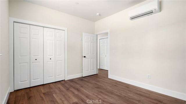 unfurnished bedroom with dark wood-type flooring, a wall unit AC, and a closet