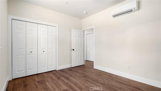 6241 Mountain View Dr, Paradise, CA 95969 - unfurnished bedroom featuring an AC wall unit, baseboards, wood finished floors, and a closet