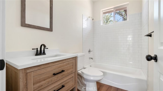 full bathroom with tiled shower / bath combo, toilet, vanity, and hardwood / wood-style floors