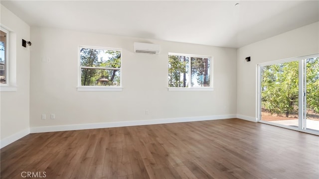 empty room featuring a wall unit AC, plenty of natural light, and dark hardwood / wood-style flooring