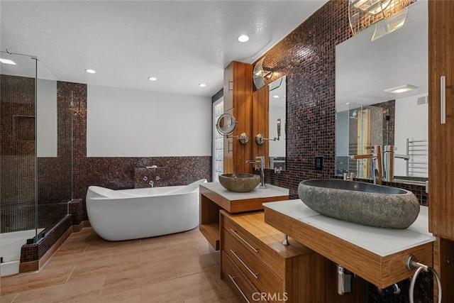 bathroom featuring vanity, tile walls, a textured ceiling, and shower with separate bathtub