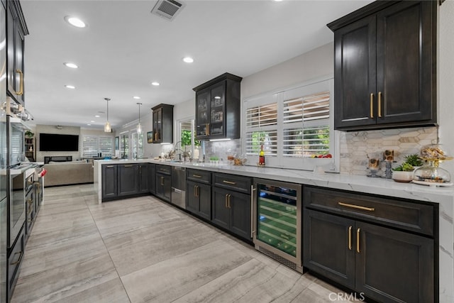 kitchen featuring wine cooler, tasteful backsplash, pendant lighting, and light stone counters