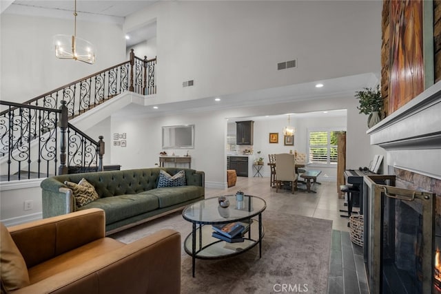 living room with a towering ceiling, crown molding, a notable chandelier, and tile patterned floors