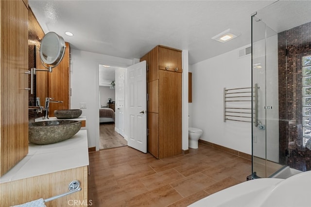 bathroom featuring a textured ceiling, a shower with shower door, hardwood / wood-style floors, toilet, and vanity