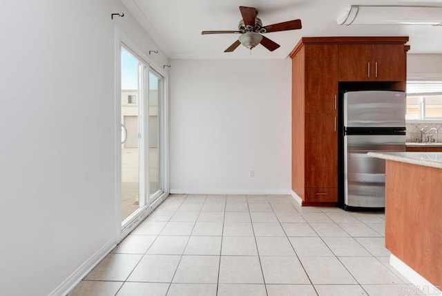 kitchen with light tile patterned flooring, ornamental molding, sink, and stainless steel refrigerator