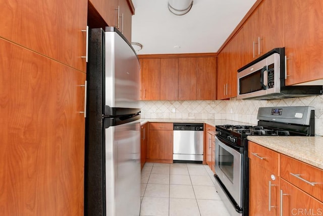 kitchen with backsplash, light stone counters, light tile patterned floors, and stainless steel appliances