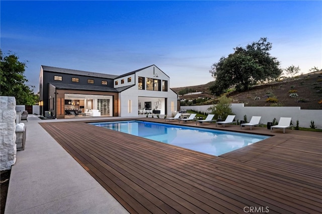 pool at dusk featuring a wooden deck