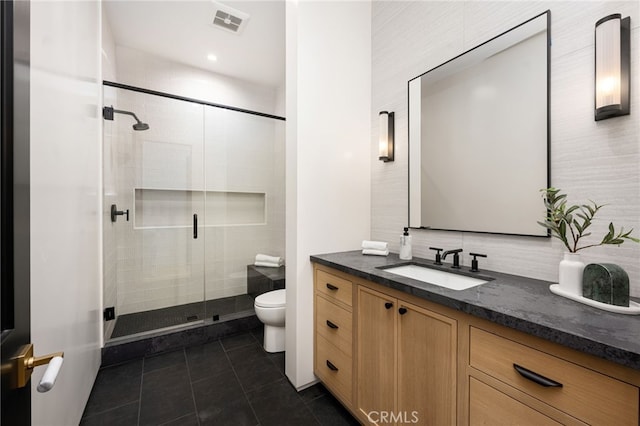 bathroom with tasteful backsplash, tile patterned floors, vanity, toilet, and a shower with shower door