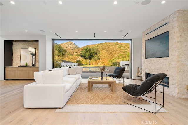 living room featuring a stone fireplace, floor to ceiling windows, and light hardwood / wood-style floors