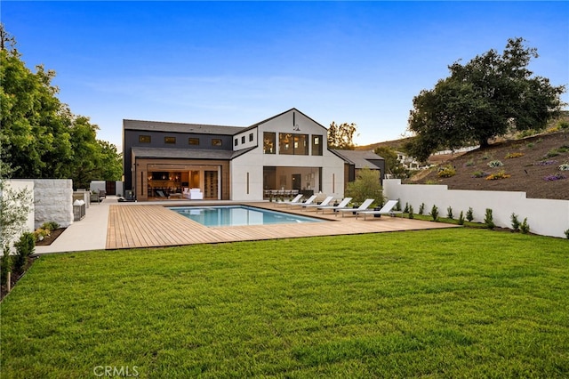 rear view of property with a fenced in pool, a lawn, a patio, and an outdoor kitchen